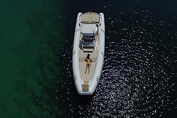 A woman is laying on the back of a boat in the water