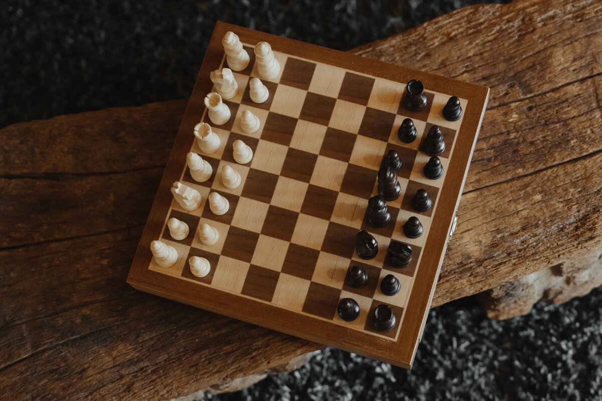 A wooden chess board with white and black pieces on it