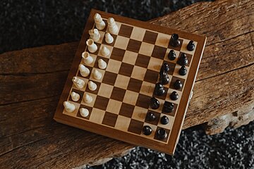 A wooden chess board with white and black pieces on it