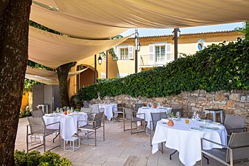 A restaurant with tables and chairs under a canopy