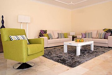 A living room with a green chair and a white coffee table