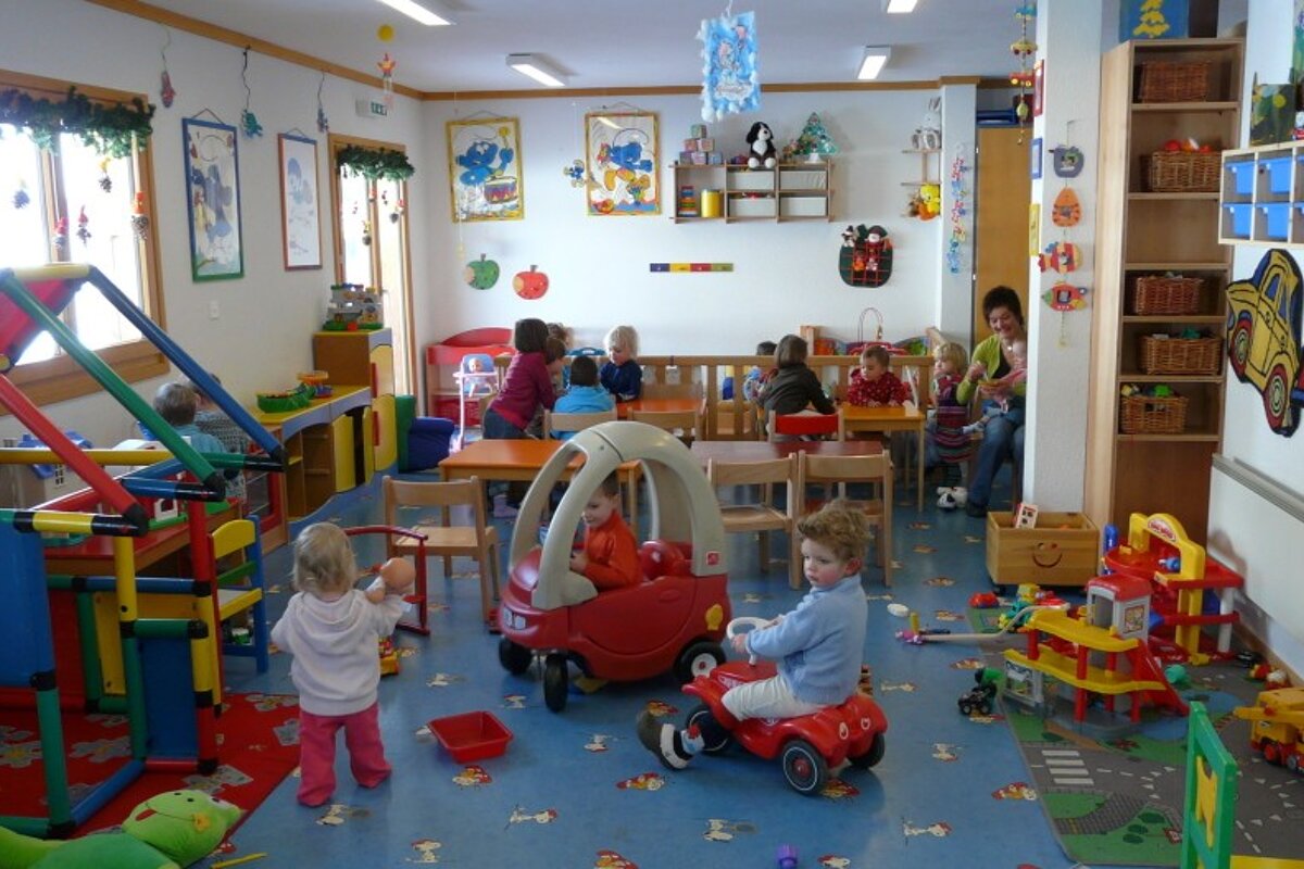 Children are playing in a room with a fire truck on the wall