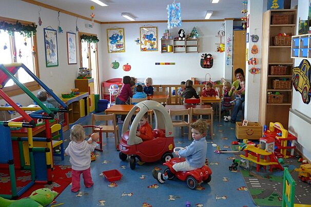 Children are playing in a room with a fire truck on the wall