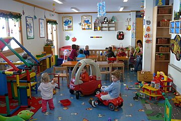 Children are playing in a room with a fire truck on the wall
