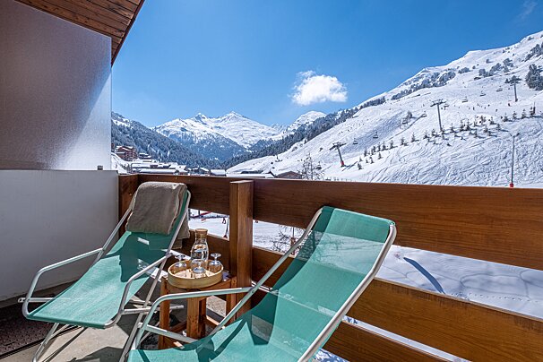 Two chairs on a balcony overlooking a snowy mountain range