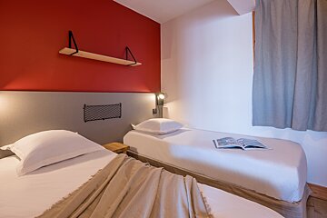 A bedroom with two beds and a book on the bed