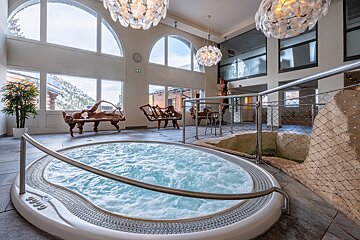 A jacuzzi in a large room with a clock on the wall