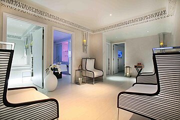 A white room with a black and white chair and a vase