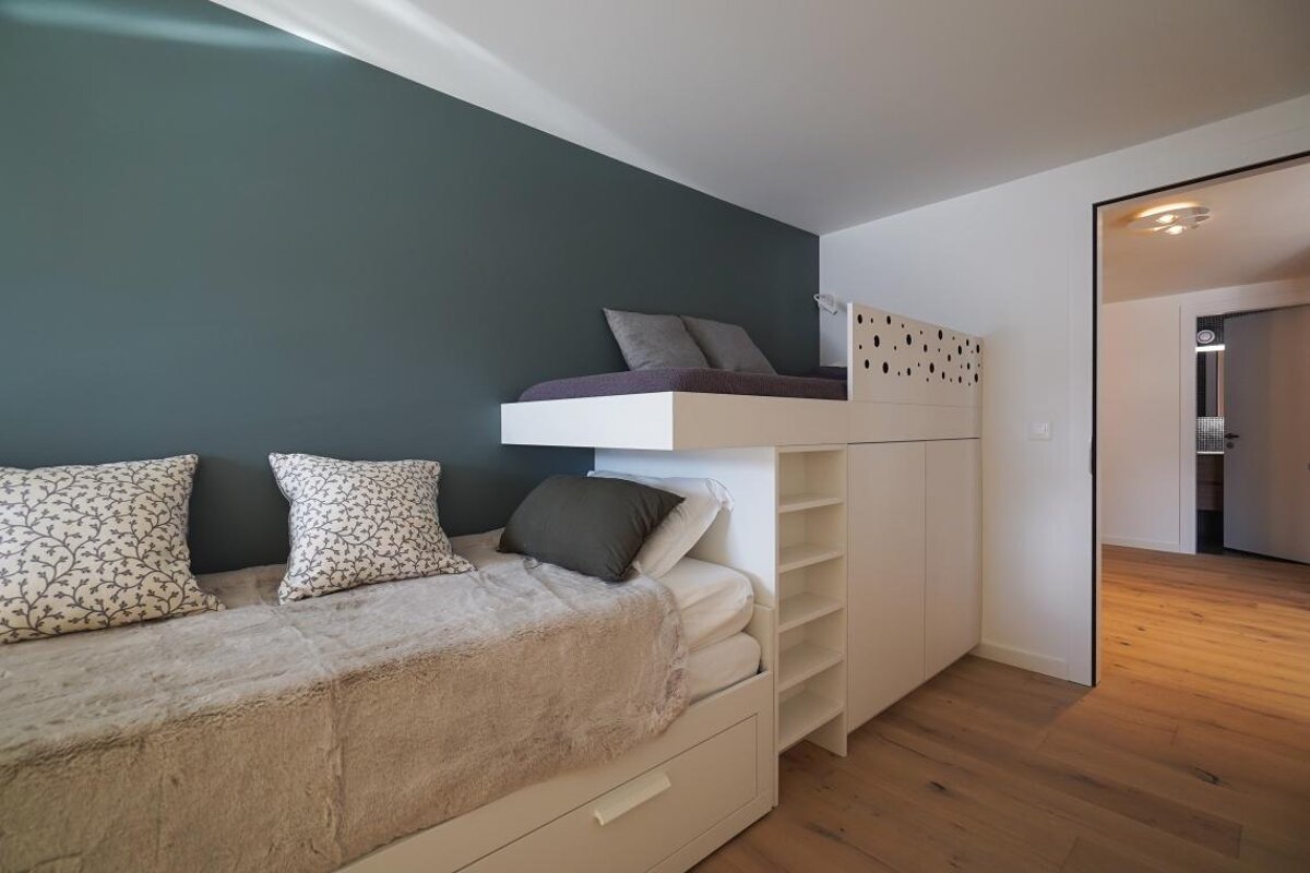 A bunk bed in a bedroom with a blue wall