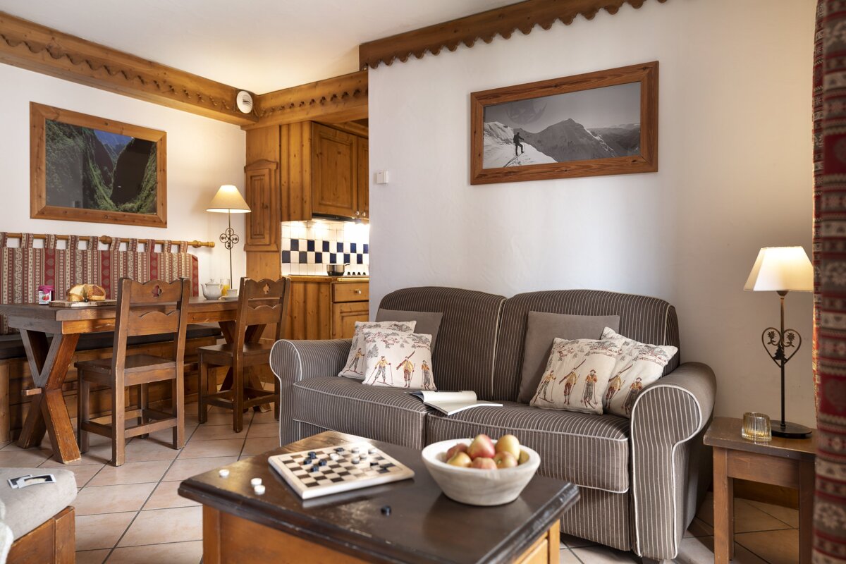 A living room with a couch and a table with a bowl of fruit on it