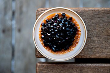 A white bowl filled with blueberries and orange sauce