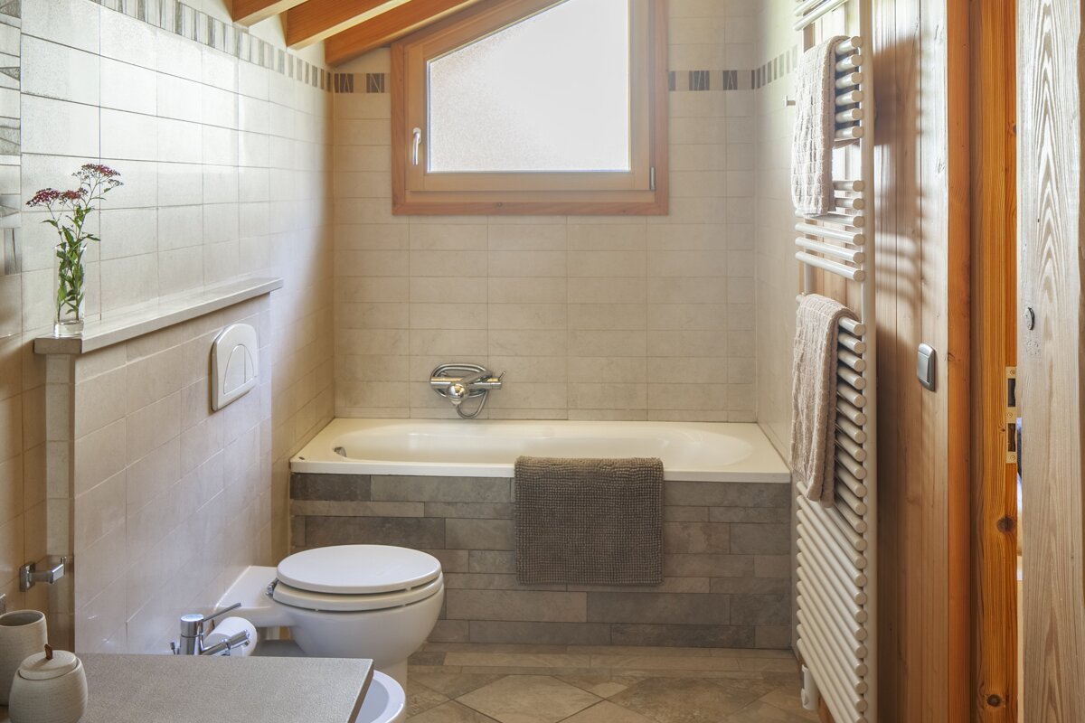 A bathroom with a toilet a bathtub and a window