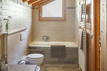 A bathroom with a toilet a bathtub and a window
