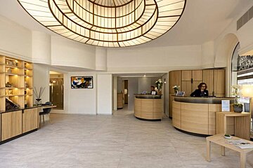 A woman stands behind a counter in a hotel lobby