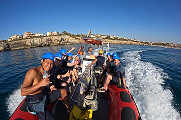 A group of people on a boat with one wearing a helmet that says ' a ' on it