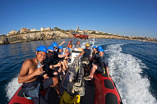 A group of people on a boat with one wearing a helmet that says ' a ' on it