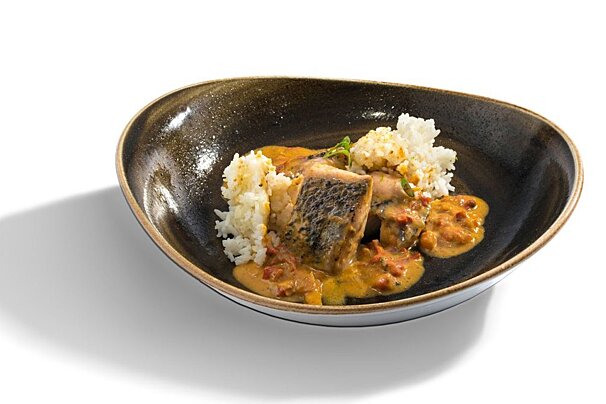 A bowl of food with rice and sauce on a white background