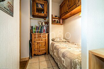 A small bedroom with a single bed and a bookshelf with a sign on the wall that says