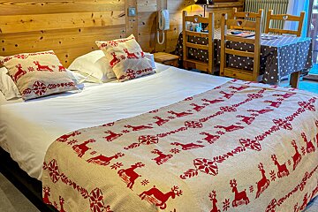 A bed with a blanket that has deer on it