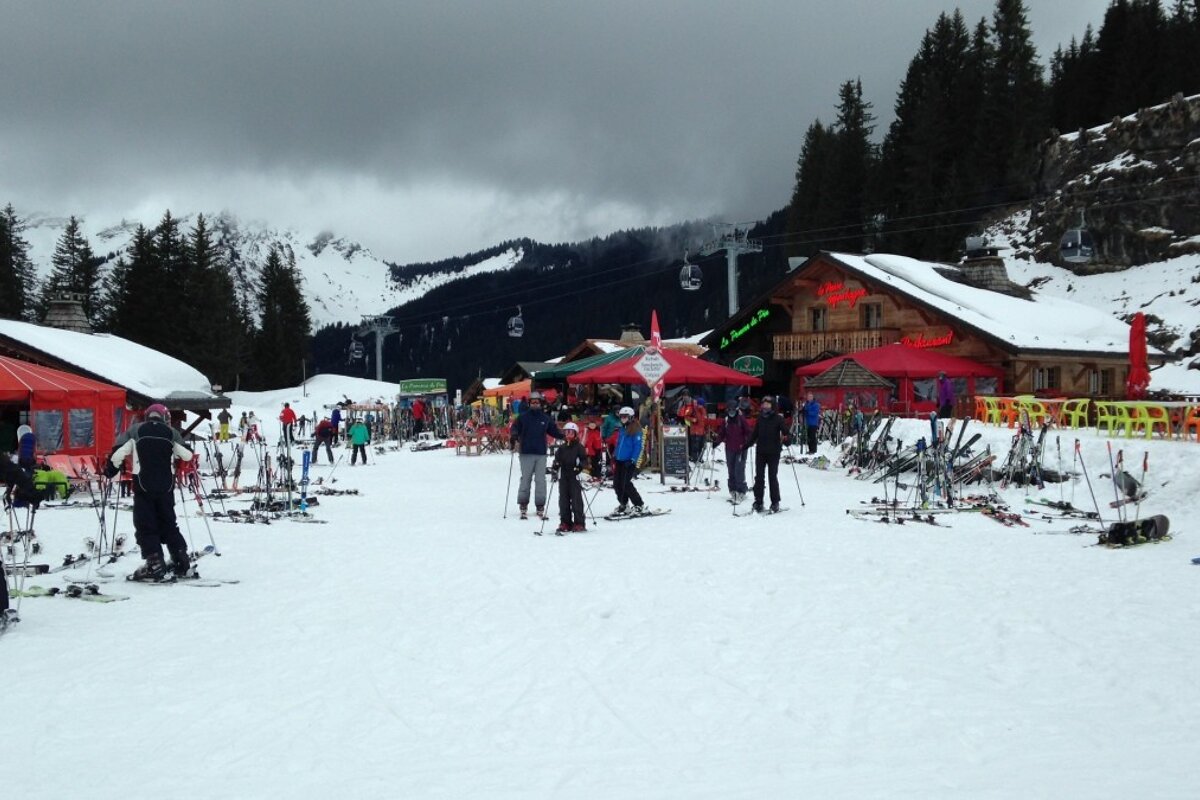 lots of people milling around cafes and restuarants byt he side of the piste
