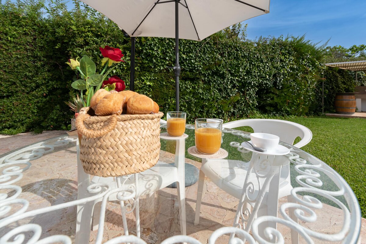 A basket of bread sits on a table next to two glasses of orange juice