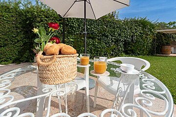 A basket of bread sits on a table next to two glasses of orange juice