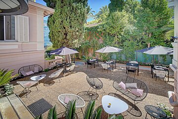 A patio with chairs tables and umbrellas in front of a building