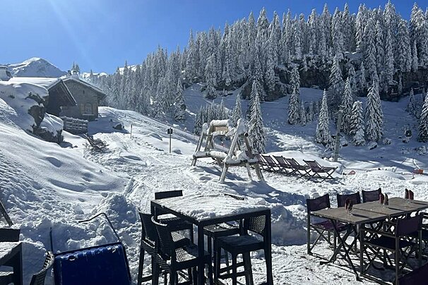A snowy landscape with tables and chairs in the foreground