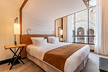 A hotel room with a bed and a table with a phone on it