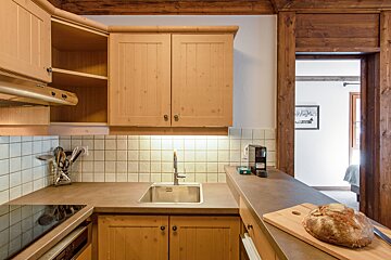 A kitchen with wooden cabinets and a cutting board with a loaf of bread on it