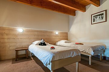 A bedroom with two beds and a picture on the wall