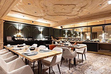 A dining room with tables and chairs and a wooden ceiling