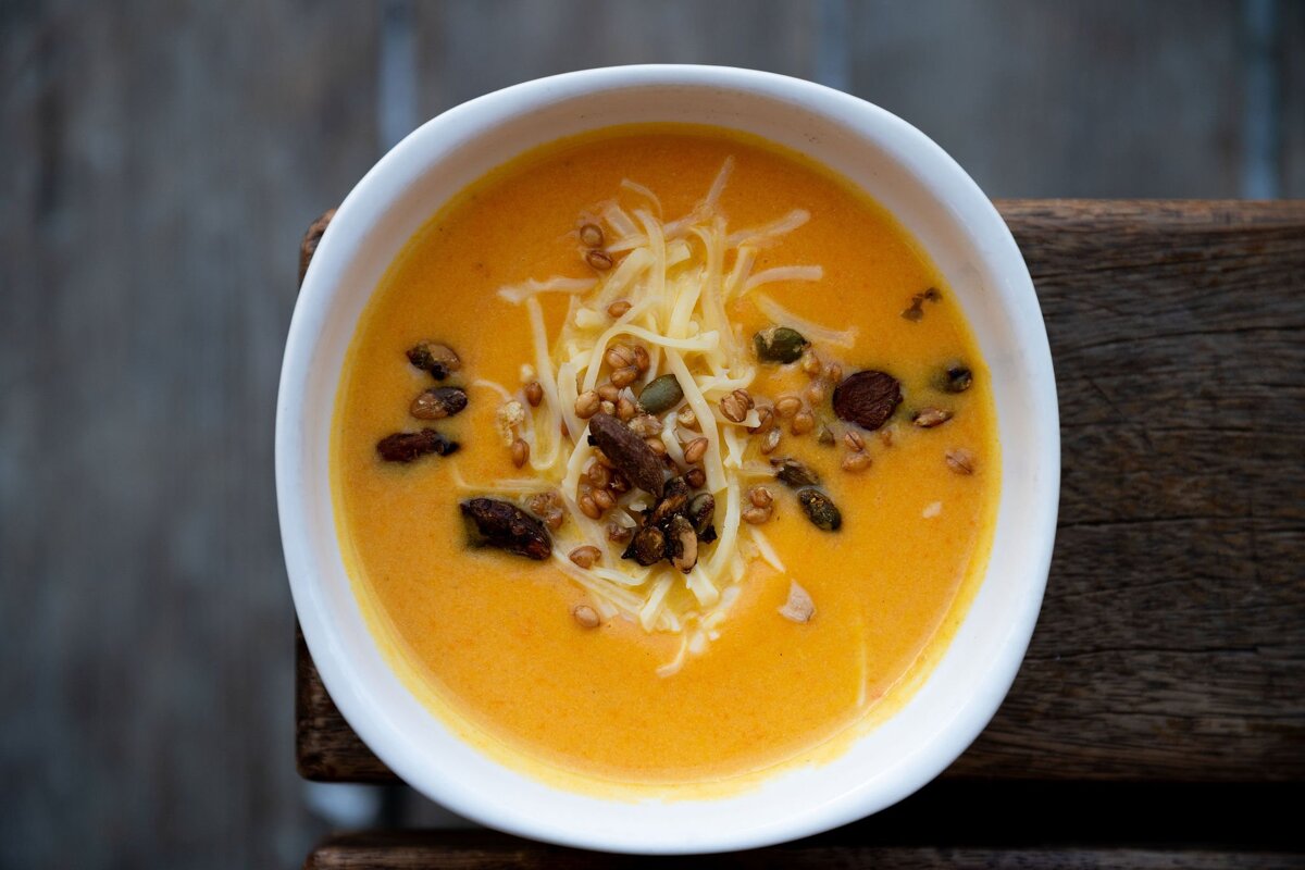 A bowl of soup with cheese and nuts on top