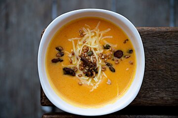 A bowl of soup with cheese and nuts on top