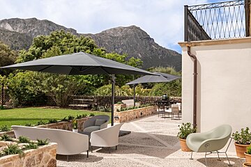 A patio with chairs and umbrellas with mountains in the background