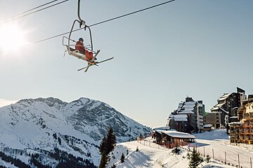 A person is riding a ski lift over a snowy mountain