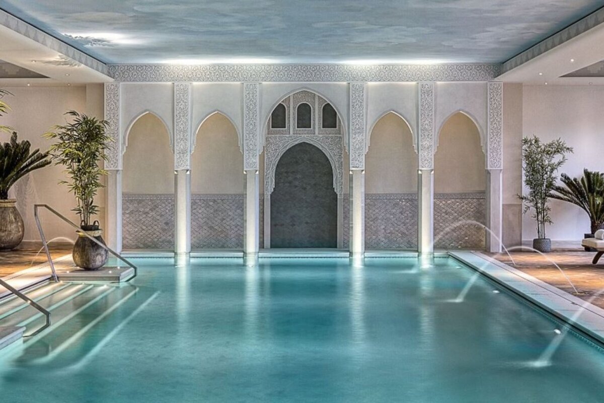 A large indoor swimming pool surrounded by plants and arches
