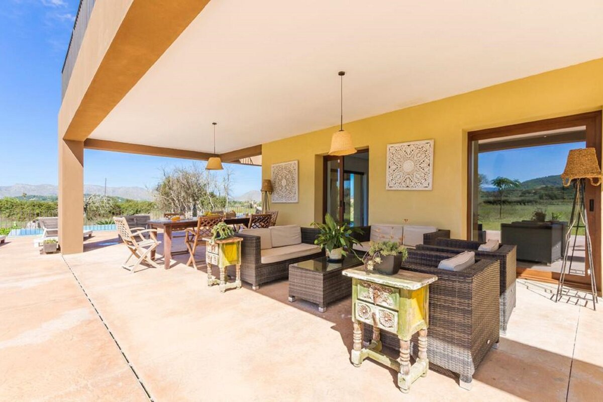 A patio with wicker furniture and a table and chairs