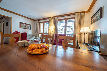 A bowl of croissants sits on a wooden table in a living room