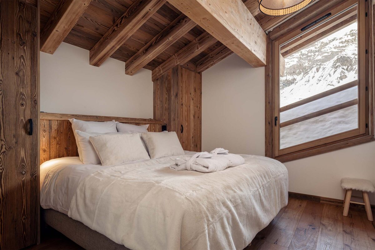 A bedroom with a bed and a window with mountains in the background