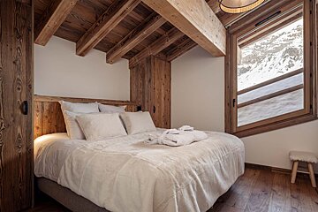 A bedroom with a bed and a window with mountains in the background