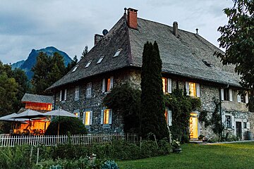 A large stone house with a mountain in the background