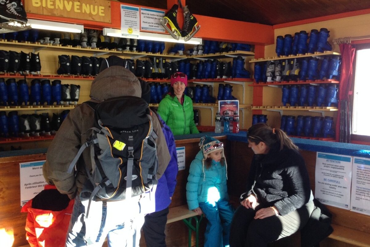 three people hiring skates in a wooden cabin