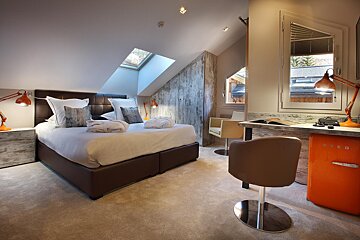 A bedroom with a bed and a small orange smeg fridge