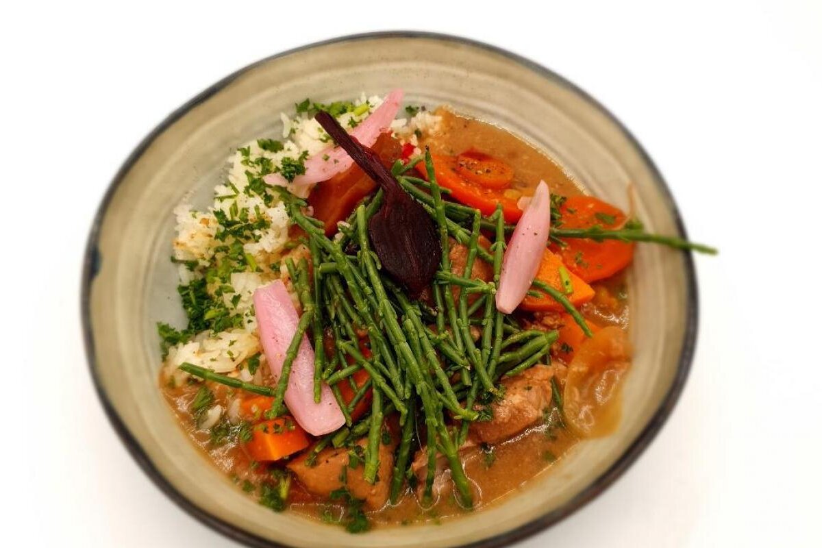 A bowl of food with carrots and rice on top