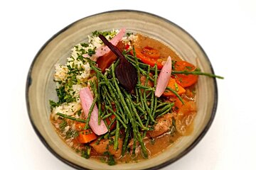 A bowl of food with carrots and rice on top