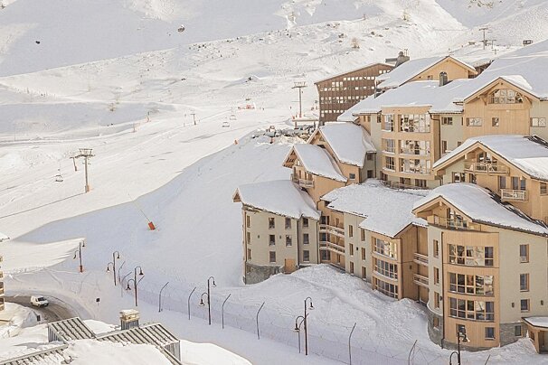 Snow covered buildings in a ski resort with a ski lift in the background