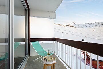 A balcony with a chair and a bottle of wine