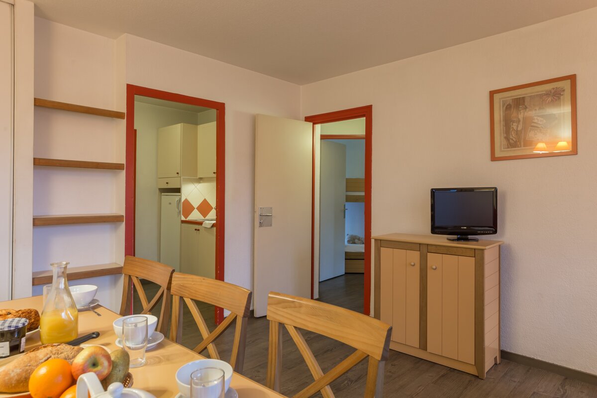 A living room with a table and chairs and a flat screen tv