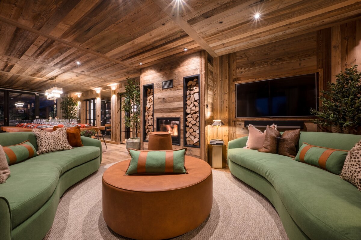 A living room with green couch and brown ottoman